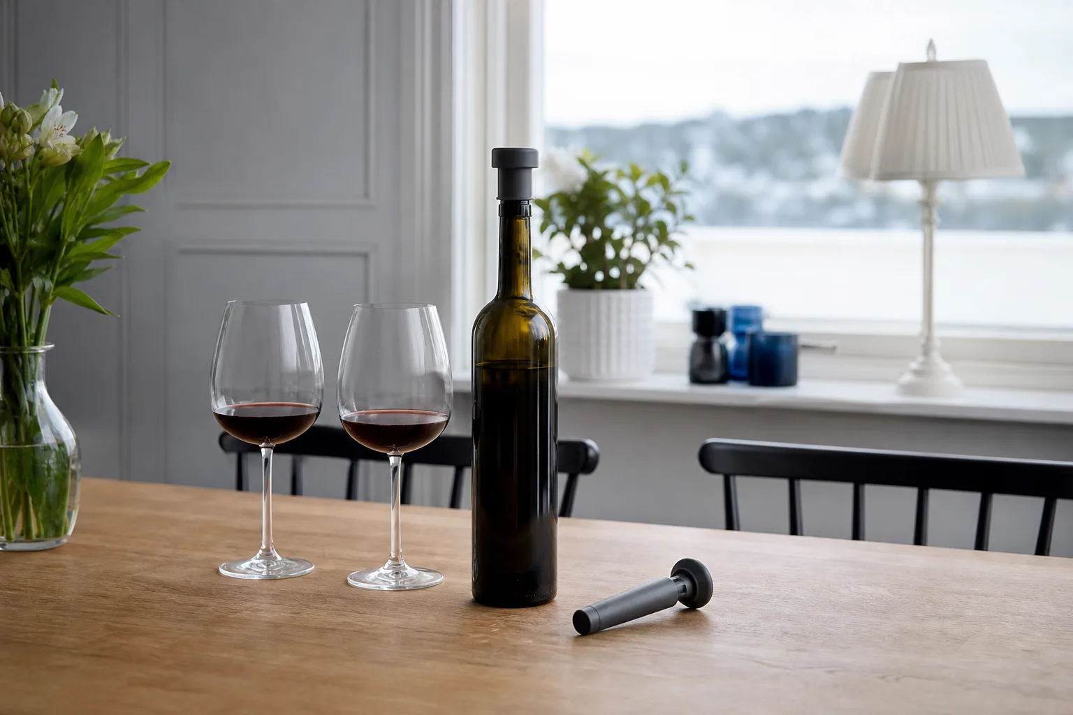 Öppnad vinflaska med vakuumpropp och vinglas